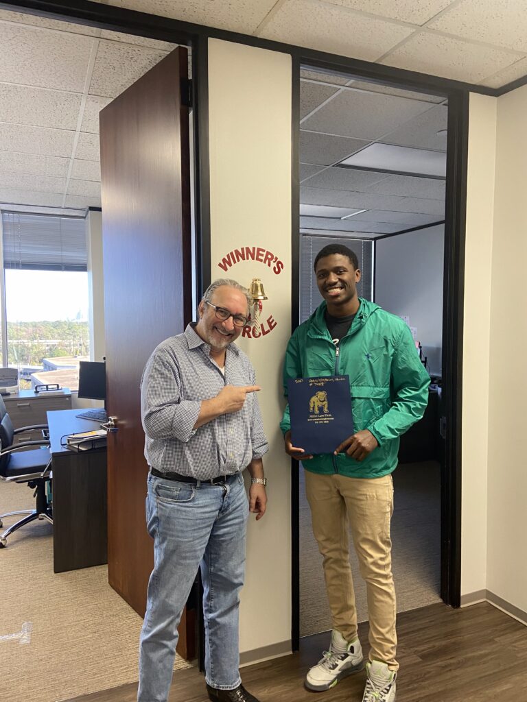 Proud client ringing the justice bell at The Texas Bulldog’s Houston office.