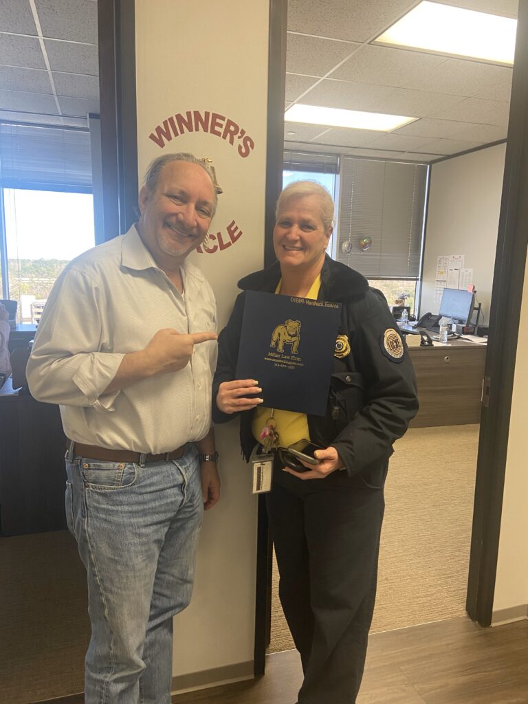 Smiling client holding settlement folder with attorney Adam Miller in Houston office.