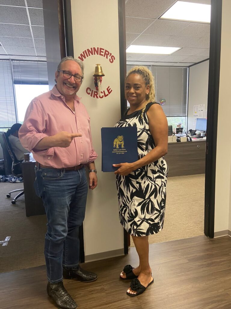 Smiling client celebrates legal victory inside The Miller Law Firm office.