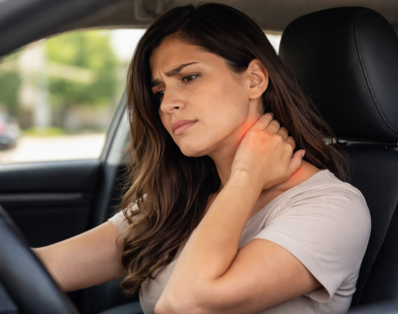 Woman sitting in her car holding her neck with delayed whiplash pain after a car accident