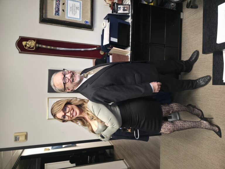 Adam H. Miller and Houston's LaLa posing back-to-back at The Miller Law Firm office while filming a TikTok video