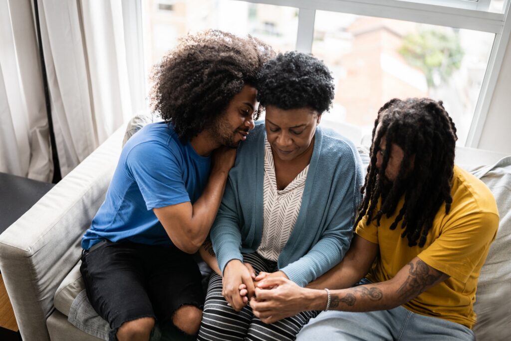 Adult sons comforting their mother at home after a family loss Adult sons comforting their mother at home, representing a family coping with a wrongful death in Texas