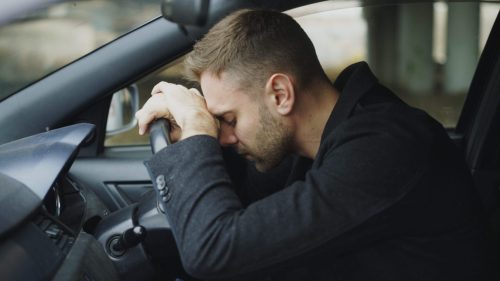 Young man sitting inside car is very upset and stressed